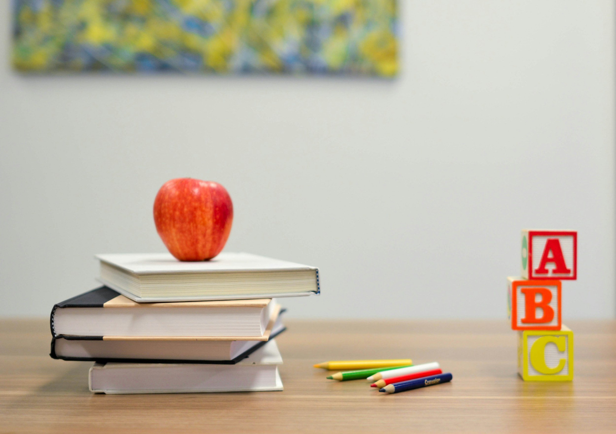 Books, an apple, colored pencils, and alphabet blocks in an early learning setting